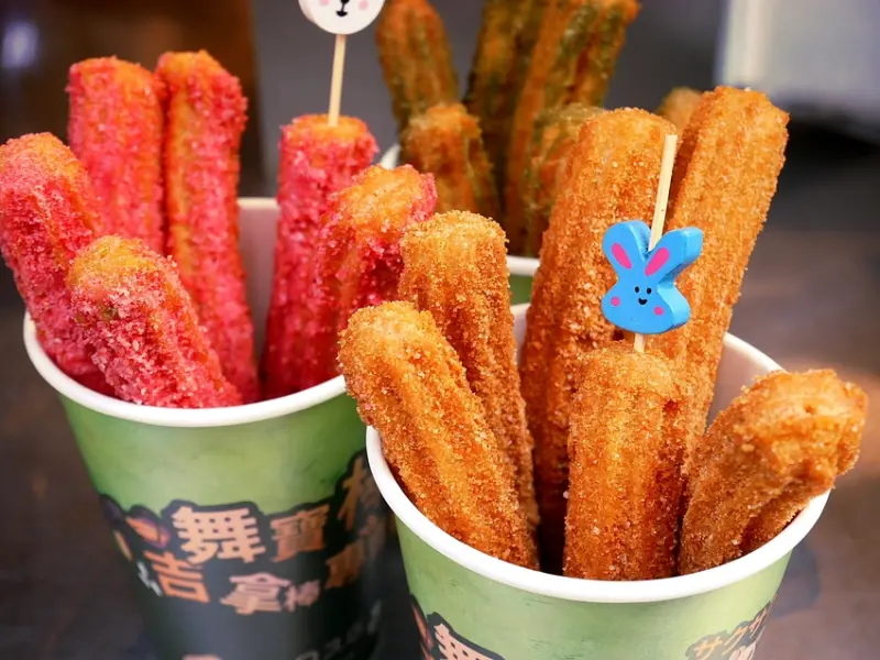 台中彩虹吉拿棒新開幕，多種口味配色超繽紛，現炸的熱騰騰金黃吉拿棒，裹上各種調味粉，立刻變成最涮嘴的下午茶