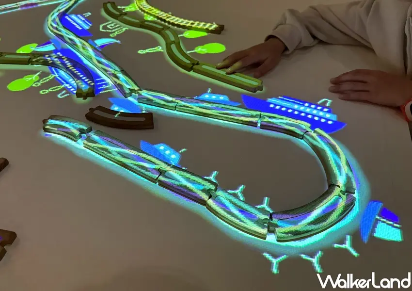 ▲寒假台北親子展覽!在桌上拼接木鐵軌,就會有小火車與樹木光影動畫出現。(攝影:鄭亦庭)