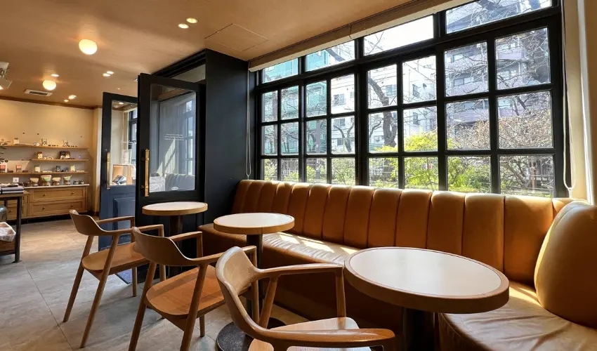 ▲坐在靠窗的小圓桌，看著路人與花雨交錯的畫面，整個畫面安靜得像一張被時間延長的底片。