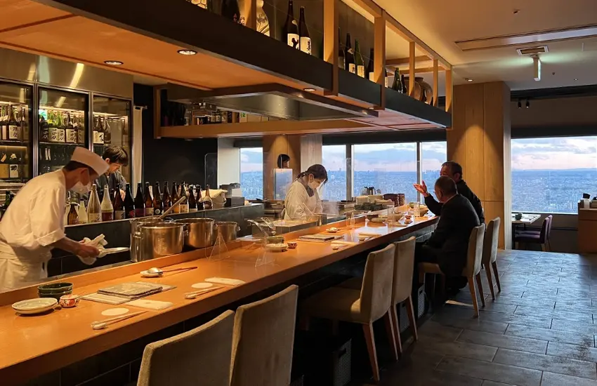 ▲站在惠比壽花園廣場38樓的玻璃窗前能欣賞東京的美，當轉身面向室內，燈光刻意壓低，吧檯圍繞著中央的湯池，那裡滾著的是一鍋看起來再熟悉不過的關東煮。