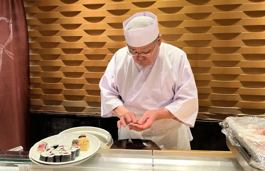 ▲師傅先在木桶上輕輕一拍，像接著用指尖捏握成形，再從木箱取出鮪魚片，指腹輕柔地貼合，手心帶出幾乎察覺不到的溫度。