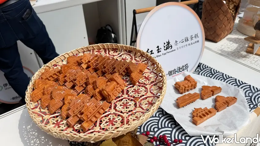 ▲人氣雞蛋糕品牌「紅玉滿赤心雞蛋糕」特別為鐵路便當節量身打造限定造型,竹篩上整齊排列著栩栩如生的蒸汽火車頭與復刻車站建築造型雞蛋糕,誘人焦糖色澤與濃郁蛋香吸引無數大小朋友前來朝聖。圖/窩客島編輯李維唐 攝