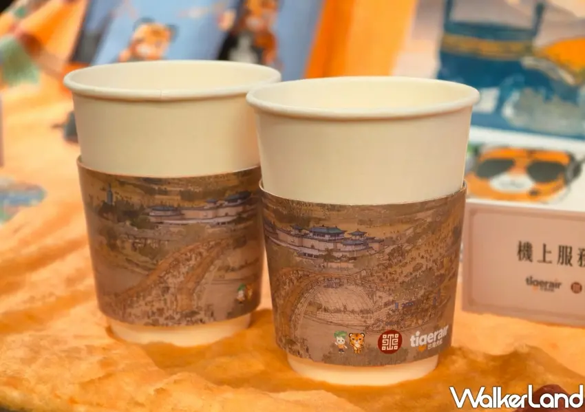 ▲台灣虎航機上隔熱紙杯套印有臺灣上河圖特別設計，融入吉祥物虎將與故宮小翠圖樣，讓旅客在機上享用飲品時體驗高空尋寶樂趣。(攝影：鄭雅之)