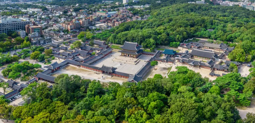 ▲遠眺世界文化遺產昌德宮全景,優雅的殿閣群與後方蔚藍天際線、綿延的山林樹海和諧共融,體現出韓國古宮順應自然的獨特建築之美。