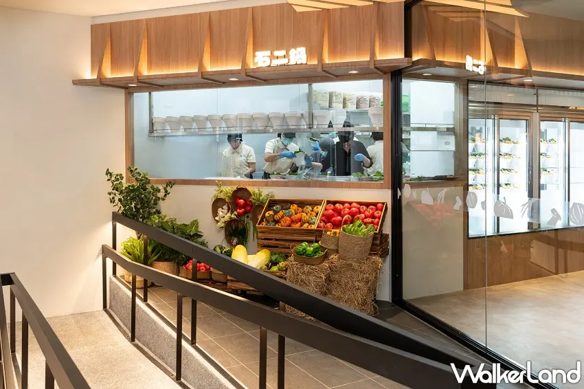 ▲石二鍋台中文心崇德旗艦店以大片玻璃呈現透明廚房,前方還擺滿各式新鮮蔬果,木質裝潢搭配明亮空間,讓準備食材的日常也成為門市特色。圖/石二鍋提供;窩客島整理