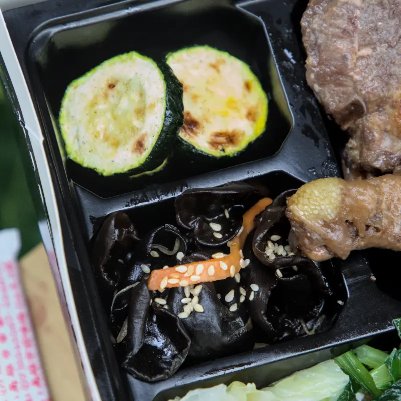 紅蕃茄客製化便當中的配菜特寫，烤櫛瓜與黑木耳絲，展現了店家對配菜的用心，確保每一份便當都能提供均衡營養與多樣口感。