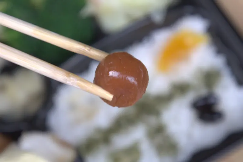 紅蕃茄便當裡店家親手醃製的日式梅子特寫，圓潤飽滿，風味清爽帶有甜味，能完美解膩，是便當裡令人驚喜的小菜。