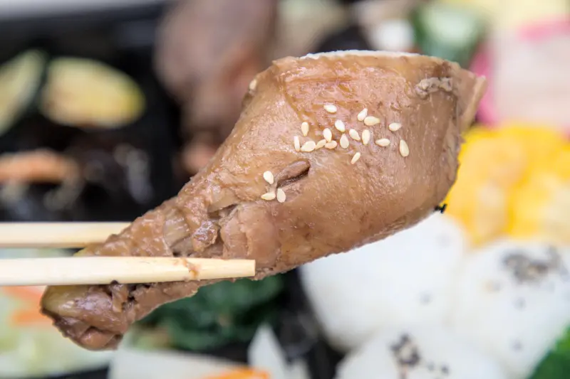 紅蕃茄客製化便當中的滷雞腿特寫，經過日式匠心慢滷，味道完整滲透到每一吋肉質，口感滑嫩入味，輕輕一咬便骨肉分離，充滿濃郁的香氣，是便當中最令人滿足的經典風味。