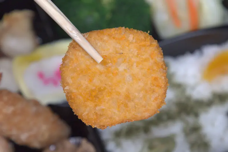 紅蕃茄小資便當中的炸鱈魚排特寫，外層麵衣輕薄酥脆，而裡面的鱈魚肉則保持著雪白細嫩的質地，口感鬆軟又帶有魚肉本身的鮮甜，是受歡迎的經典主菜。