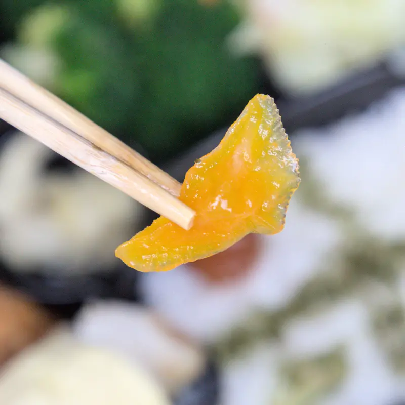 紅蕃茄便當裡黃澄澄的醃地瓜特寫，地瓜口感脆度十足，浸泡在酸甜醬汁中，吃起來爽口又開胃，是外面少見的獨家小菜。