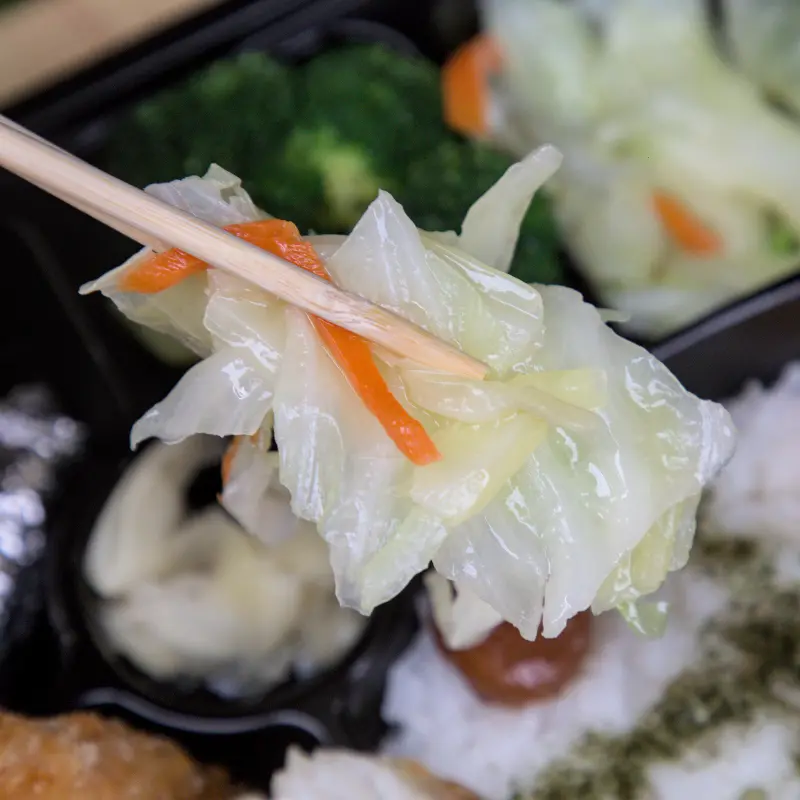 紅蕃茄便當的清炒高麗菜與花椰菜特寫，店家堅持使用台灣高山尖頭高麗菜，即使颱風季菜價飆漲也不更換，展現對食材品質的固執與堅持。