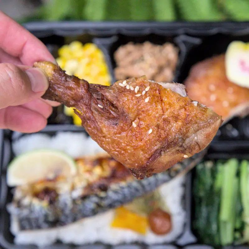 紅蕃茄250元三拼便當中的炸雞腿特寫，炸得金黃酥脆的外皮，保有滿滿肉汁，口感軟嫩多汁，香氣十足，是便當界的經典美味。